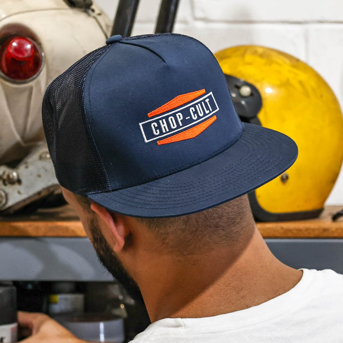 Person wearing a navy blue cap with 'CHOP-CULT' logo in an industrial setting