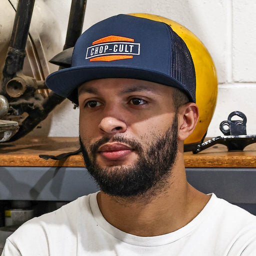 Man wearing a navy blue cap with 'CHOP CULT' logo in a workshop setting