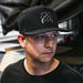 Man wearing a black cap with a logo, looking off to the side.