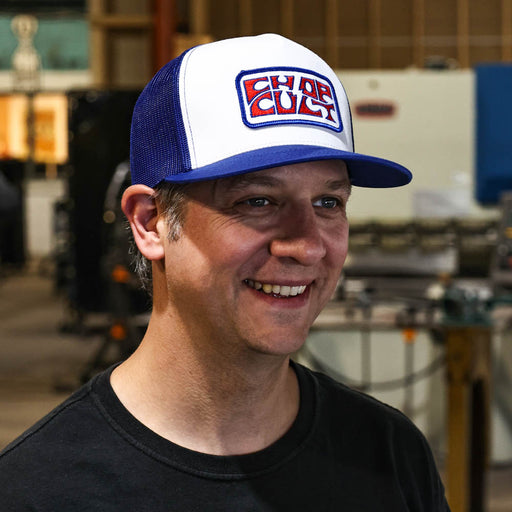 Man wearing a white and blue cap with ' Cult' logo in an indoor setting